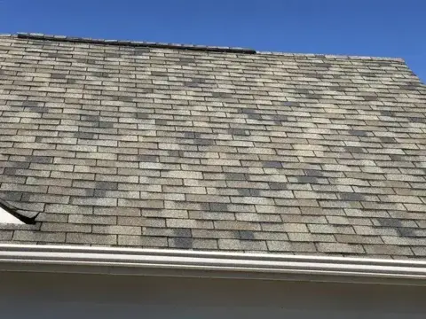 Shingle roof condition with missing shingles near the ridge